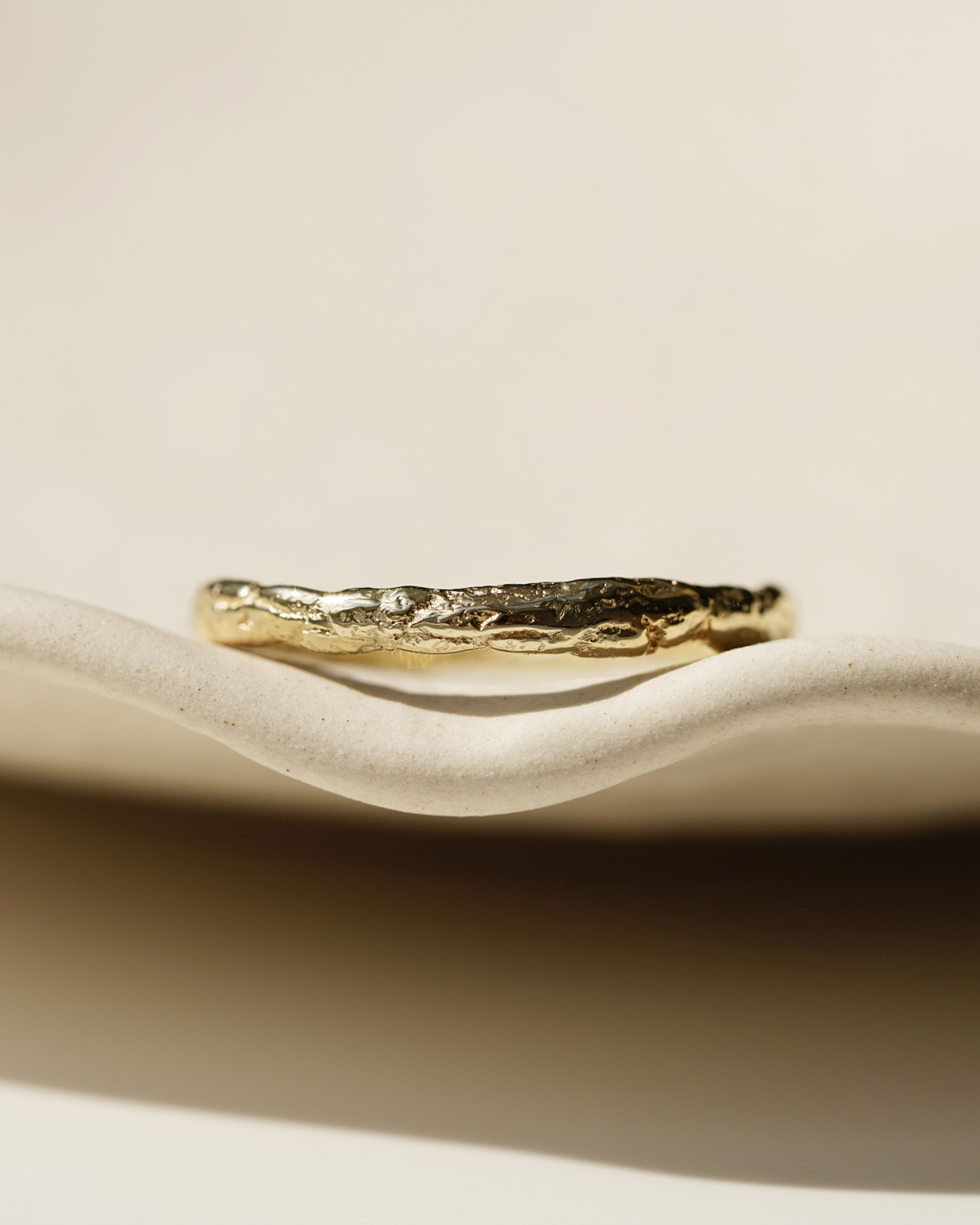 textured gold ring on a clay tray